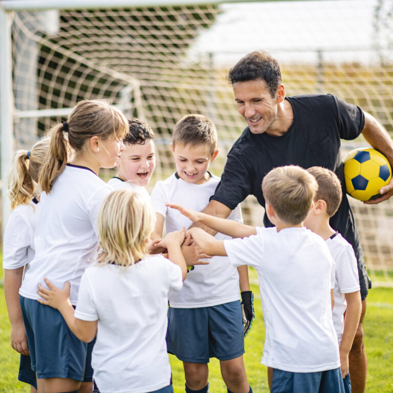 Kids celebrating after a soccer game with their coach