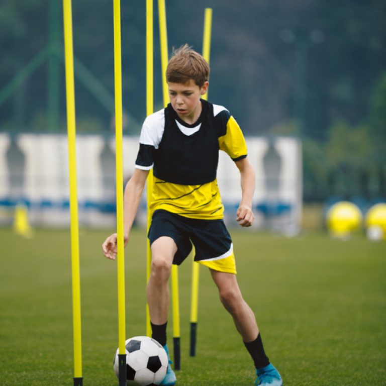 Soccer Players Running With Balls in Between Training Poles. Football Practice Session for Youth Sports Club